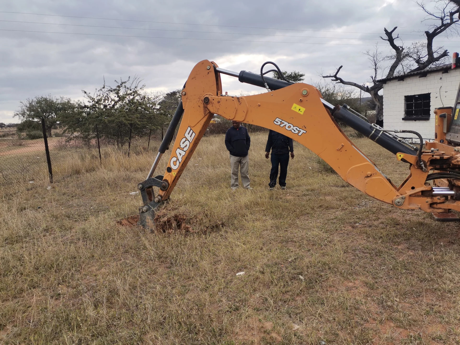 Geotechnical engineering – soil investigation on site using a backhoe excavator, with engineers overseeing ground sampling for foundation analysis.