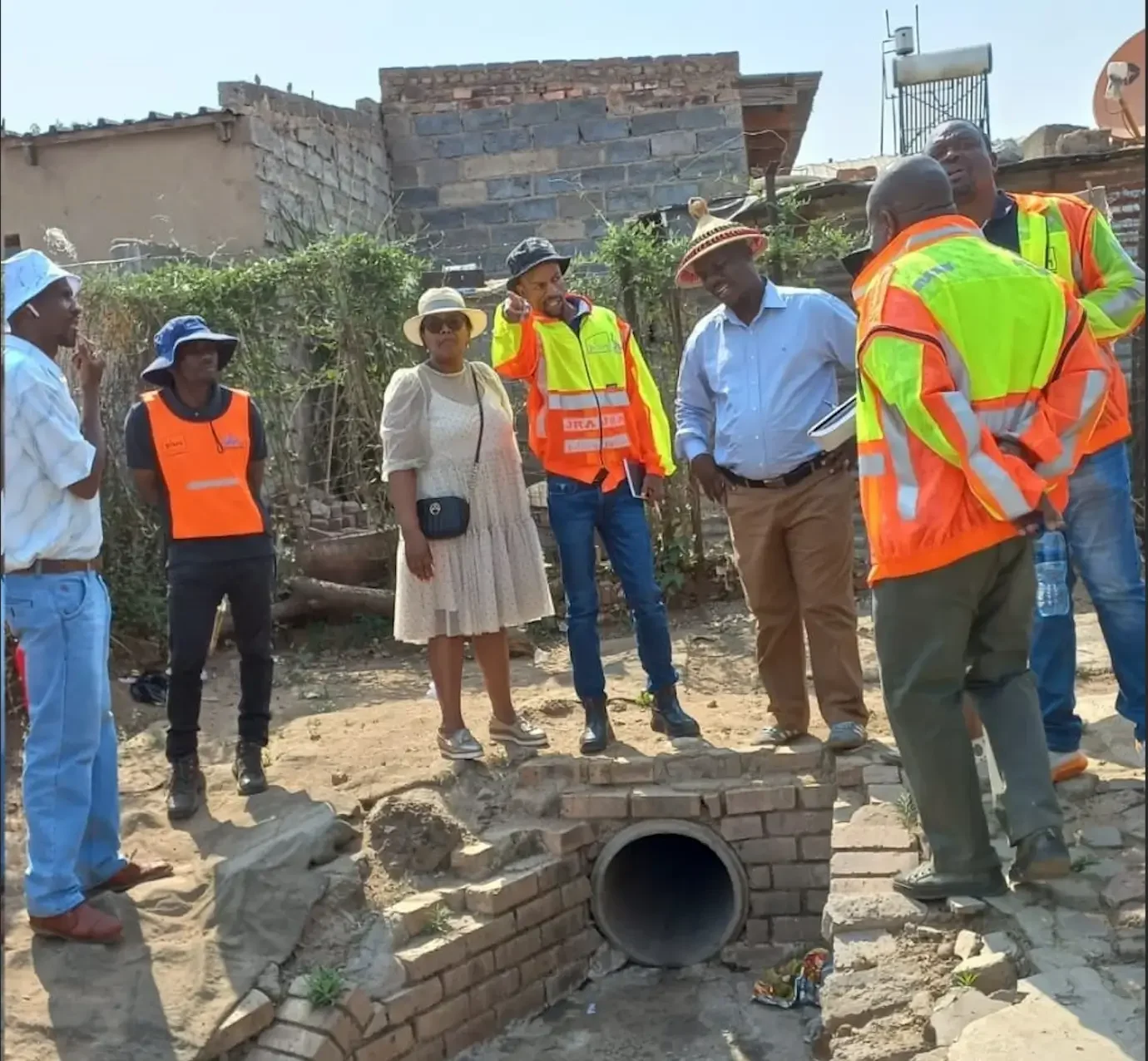 Infrastructure advisory – engineers and community members inspecting a drainage pipe installation and discussing project planning on site.
